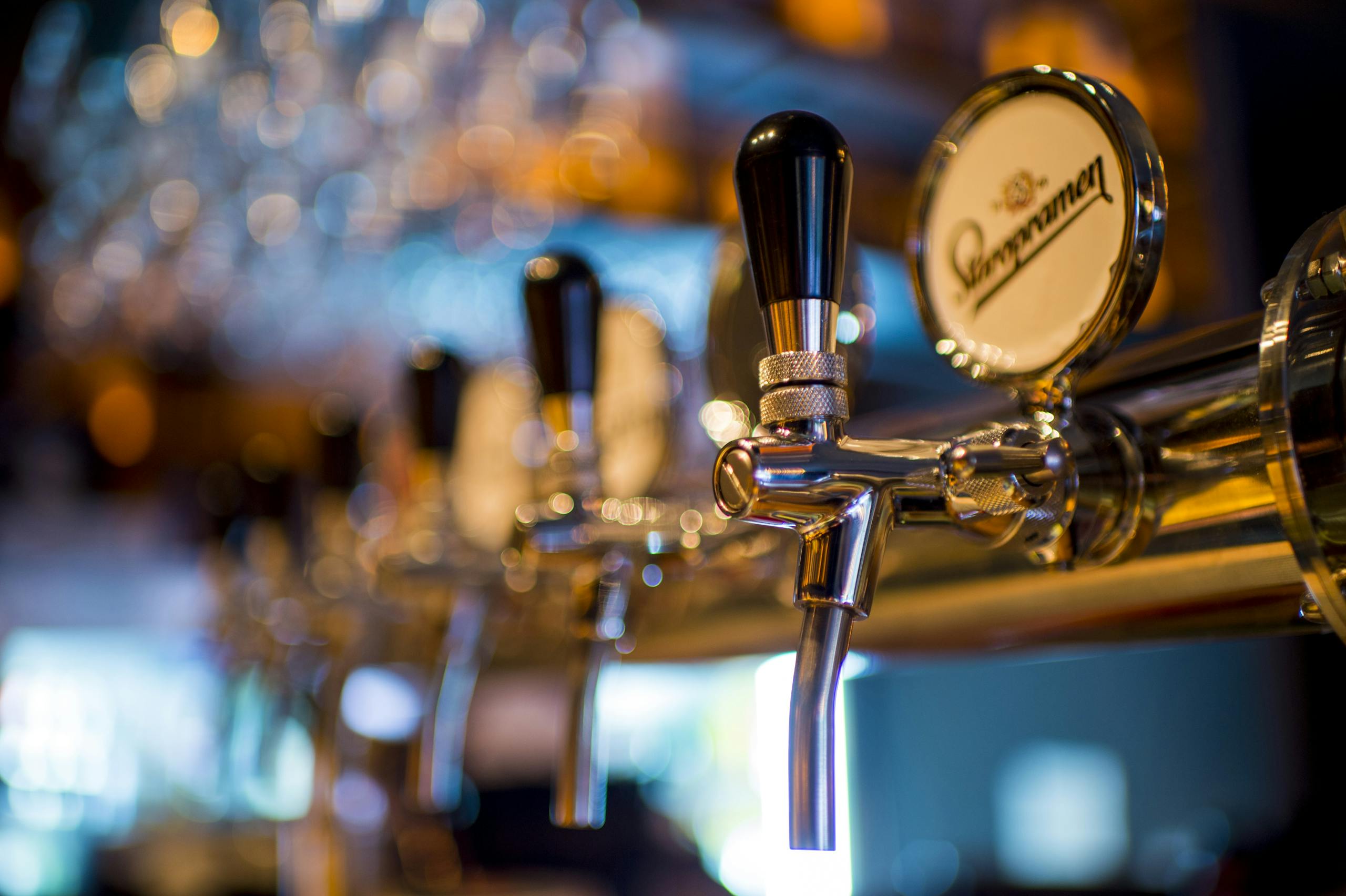 Focused image of a shiny beer tap in a stylish bar with a blurred background.